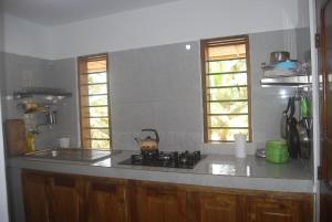 a kitchen with a stove and a sink and two windows at Laguna Lodge in Ouidah +32 photos