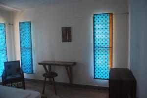 a room with a table and blue glass windows at Laguna Lodge in Ouidah