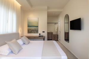 a bedroom with a white bed with a flat screen tv at Phos Luxury Living in Sarti