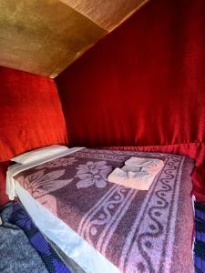 a small bed in a room with a red wall at Traditional nomad camp in Merdani