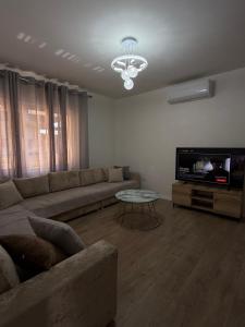 a living room with a couch and a tv at Olivea Suites Tirana in Tirana