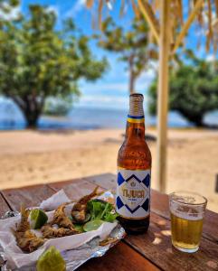 a bottle of beer and a plate of food on a table at Pousada Serena - Alter do Chão in Santarém