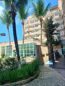 a building with palm trees in front of it at Apart Itacuruçá - Hotel Porto Marina in Mangaratiba