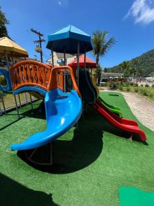 a playground with a slide and an umbrella at Apart Itacuruçá - Hotel Porto Marina in Mangaratiba