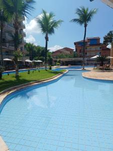 a large swimming pool with palm trees in the background at Apart Itacuruçá - Hotel Porto Marina in Mangaratiba