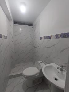 a white bathroom with a toilet and a sink at Casa Blanca in Ayacucho