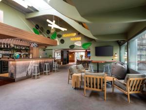 a restaurant with chairs and a bar with a tv at IBIS STYLES Rouen Parc Expos Zenith in Saint-Étienne-du-Rouvray