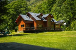a large wooden house on top of a grass field at Refugio Las Raices in Malalcahuello