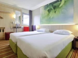 a hotel room with two beds and a painting on the wall at ibis Styles Paris Roissy-CDG in Roissy-en-France +52 photos