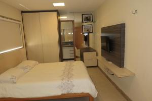 a small bedroom with a bed and a television at Porto Brasil Resort - Casa de praia em condomínio de luxo in Parnamirim