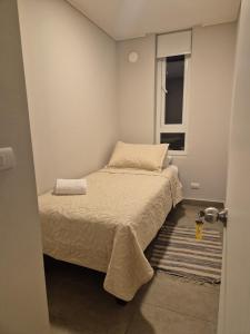 a small bedroom with a bed and a window at Depto cómodo y central in Temuco +1 photo