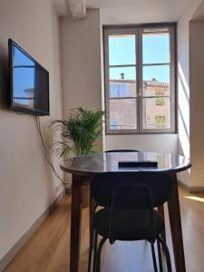 a table in a room with a tv and a window at Dubonnet - Cœur de ville in Brignoles