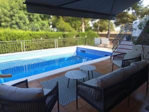 a pool with chairs and tables and an umbrella at Casa Azahar in Lliria