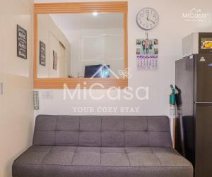 a couch in a room with a clock on the wall at MiCasa South Residences Cozy & Affordable Stay in Manila