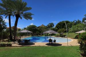 a pool with tables and chairs and umbrellas at Porto Brasil Resort - Casa de praia em condomínio de luxo in Parnamirim