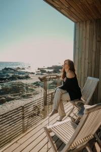 a woman sitting on a porch looking out at the beach at Hotel 8 al Mar in Pichilemu +11 photos