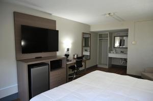 a hotel room with a bed and a flat screen tv at Whalers Inn and Suites in New Bedford