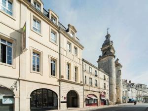 a building with a clock tower next to a street at ibis Styles La Rochelle Centre Vieux Port in La Rochelle