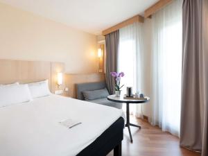a hotel room with a bed and a table with flowers at ibis Nancy Centre Gare et Congres in Nancy +120 photos