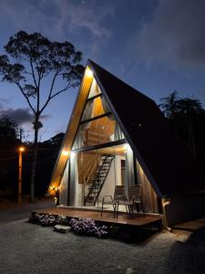 a small house with a black roof and two chairs at Morro dos Chalés in Pomerode