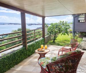 a patio with chairs and a table with a view of the water at Tahiti Roa Lodge Faaa in Faaa