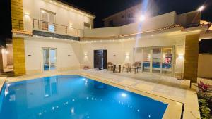 a swimming pool in front of a house at night at فيلا الكينج مريوط in King Mariout