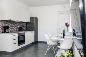 a kitchen with white cabinets and a table with white chairs at Apartments Zdeslav in Rogoznica