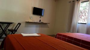 a bedroom with a bed and a tv on the wall at pousada recanto gerais in Carmo do Rio Claro