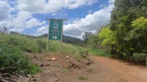 a green sign on the side of a dirt road at pousada recanto gerais in Carmo do Rio Claro