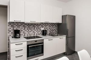 a kitchen with white cabinets and a refrigerator at Apartments Zdeslav in Rogoznica