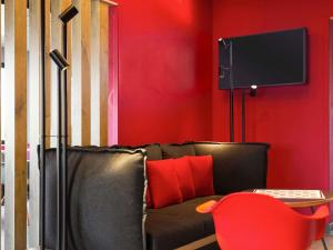 a living room with a black couch and a red wall at ibis Hotel Brussels Airport in Diegem