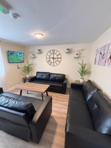 a living room with two black leather couches and a table at Glancy's Accommodation in Carrick on Shannon