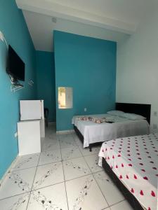 a bedroom with two beds and a blue wall at Pousada Paraiso in Canudos