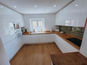 a kitchen with white cabinets and a wooden floor at Villa Frescura do Mar by Casas de Setúbal in Setúbal +40 photos