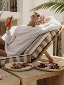 a woman laying in a chair with a table with plates of food at Hotel Panamera in Tulum +40 photos