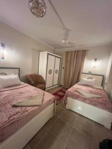a bedroom with two beds and a chair at Backpacker Room 2 in Aswan