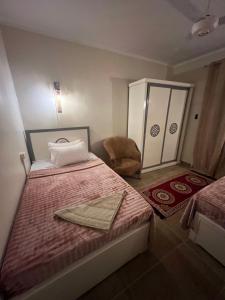 a small bedroom with two beds and a chair at Backpacker Room 2 in Aswan
