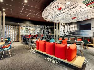 a restaurant with red chairs and tables and a tv at ibis Poitiers Site du Futuroscope in Chasseneuil-du-Poitou