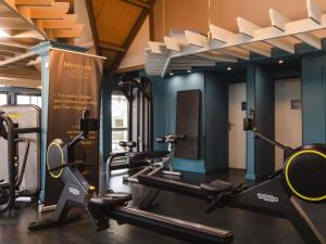 a gym with several tread machines in a room at Mercure Cabourg Hôtel & Spa in Cabourg