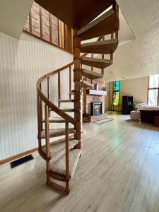 Eine hölzerne Wendeltreppe in einem Wohnzimmer mit Kamin in der Unterkunft Falling Timber- A Frank Lloyd Wright Inspired Staycation in Canton