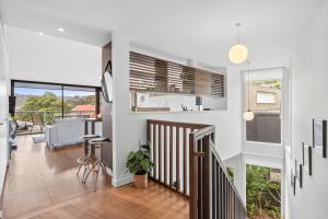 a living room with white walls and a staircase with a table at Breakers Holiday House in Lorne