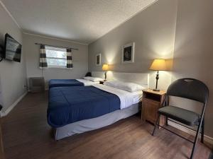 a bedroom with a large bed and a chair at Mountain View Motel in Barrys Bay