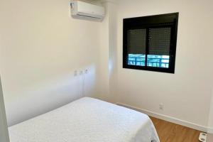 a white room with a bed and a window at APARTAMENTO PRÓXIMO AO CENTRo in Joinville