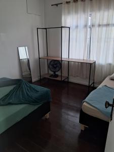 a room with two beds and a table in it at Pousada Paula Lima I in Juiz de Fora