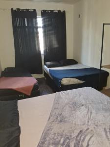 a room with three beds and a window at Pousada Paula Lima I in Juiz de Fora
