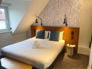 a bedroom with a large white bed with blue pillows at ibis Colmar Centre in Colmar