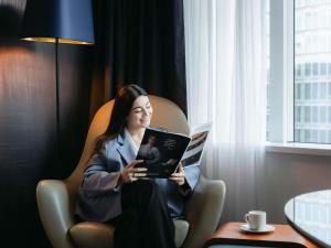 a woman sitting in a chair with a laptop at Sofitel Luxembourg Europe in Luxembourg