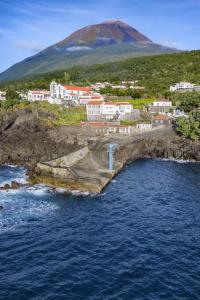 an island with a town and a mountain in the background at Casa da Guarda in São João +12 photos