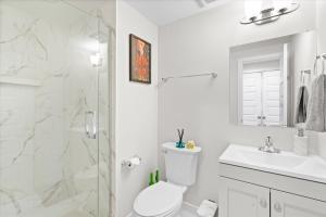 a white bathroom with a shower and a toilet and a sink at Entire DC House 2BR 2BA Fire Pit Free Parking Near Capitol Hill in Washington, D.C. +7 photos