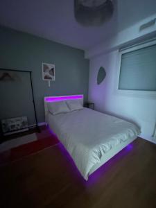 a bedroom with a bed with a purple light on it at Appartement moderne avec parking privé Lit connecté LED & rétroprojecteur 5 min Zénith in Saint-Herblain